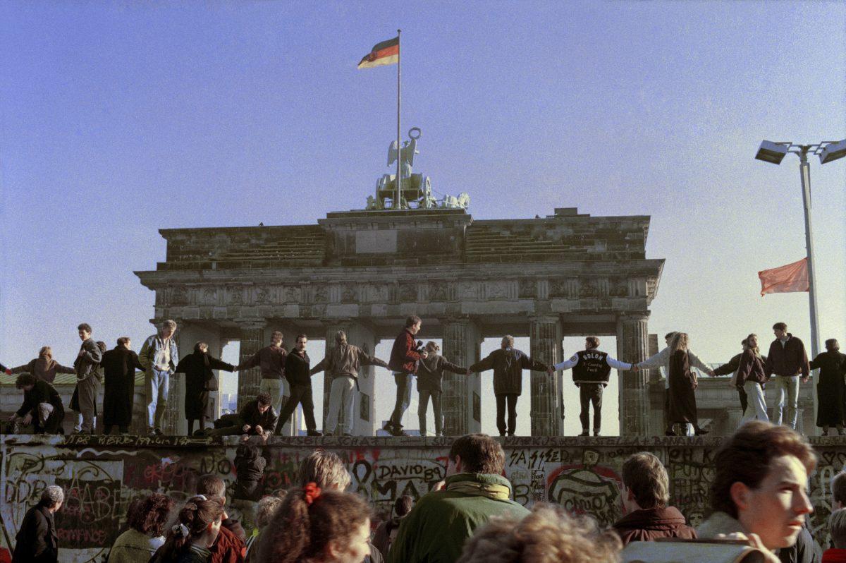 Berliners sing and dance on top of The Berlin Wall to celebrate the opening of East-West German borders. Thousands of East German citizens moved into the West after East German authorities opened all border crossing points to the West. In the background is the Brandenburg Gate, on Nov. 10, 1989. (AP Photo/Thomas Kienzle)