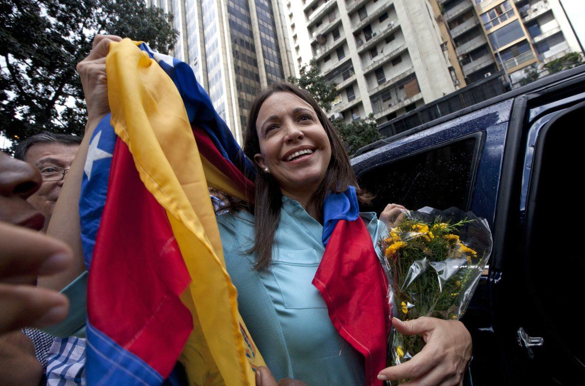 Former lawmaker and opposition leader Maria Corina Machado holds up the Venezuelan flag outside of the attorney general's office in Caracas, Venezuela, on Dec. 3, 2014. (Ariana Cubillos/AP Photo)