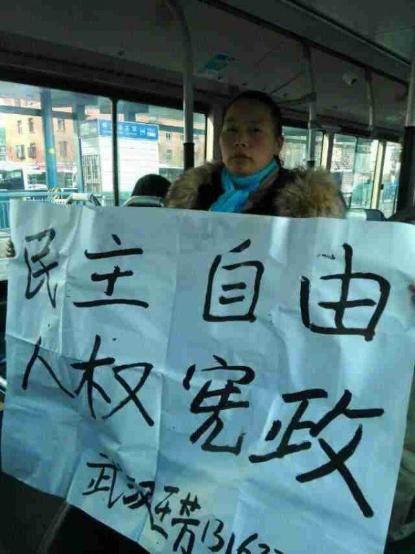 Petitioner Wang Fang from Hubei Province holds a banner saying "Democracy, freedom, human rights, constitution" on a bus she was placed on by police in Beijing, on Dec. 4, 2014. It was China's newly established Constitution Day, but thousands of aggrieved petitioners found little to celebrate. (New Tang Dynasty Television)