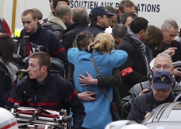 People hug each other outside Charlie Hebdo's office, in Paris, on Jan. 7, 2015. (AP Photo/Remy de la Mauviniere)