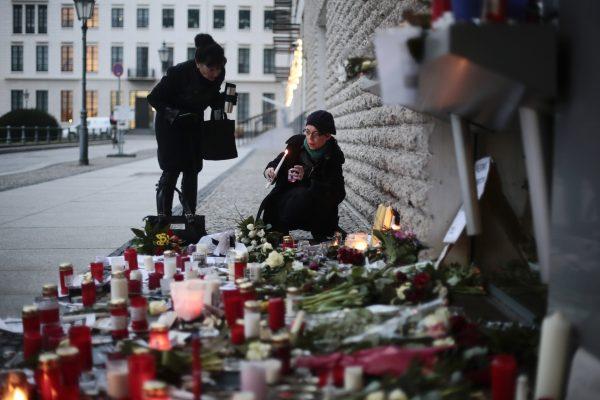 Women light candles to commemorate the victims killed in an attack at the Paris offices of the weekly newspaper Charlie Hebdo, in front of the French Embassy in Berlin, on Jan. 8, 2015. (AP Photo/Markus Schreiber)