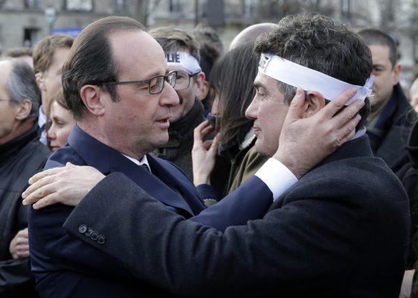French President Francois Hollande, left, comforts French columnist for Charlie Hebdo Patrick Pelloux as they take part with family members and relatives in a solidarity march in the streets of Paris on Jan. 11, 2015. (AP Photo/Philippe Wojazer, Pool)