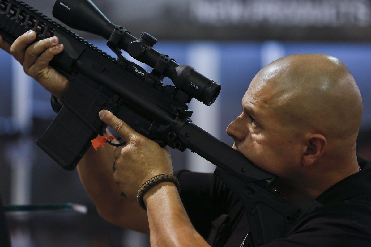 A police officer is looking through the sight of a rifle at the Shooting Hunting and Outdoor Trade Show in Las Vegas, on Ja.14 2019. (AP Photo/Julie Jacobson)