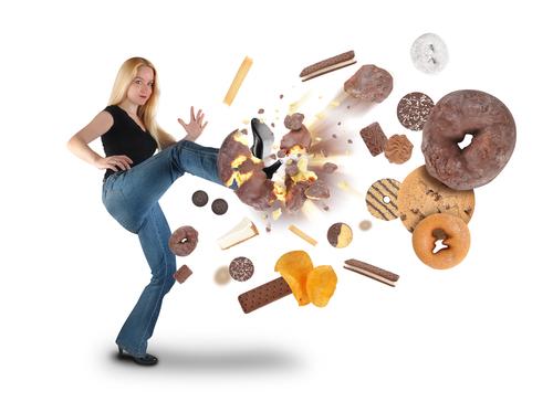 The first step to proper immune function is to largely eliminate the worst offenders in its suppression. (<a href="http://www.shutterstock.com/pic-92733478/stock-photo-a-young-woman-is-kicking-a-donut-on-a-white-background-within-an-assortment-of-junk-food-there-are.html?src=DyQTEFxqBQGx8K7b3japmQ-1-0&ws=1" target="_blank" rel="noopener">Shutterstock</a>*)