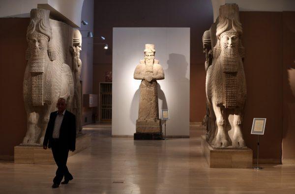 A man walks past two ancient Assyrian human-headed winged bull statues at Iraq's National Museum in Baghdad on March 1, 2015. (Karim Kadim/AP Photo)