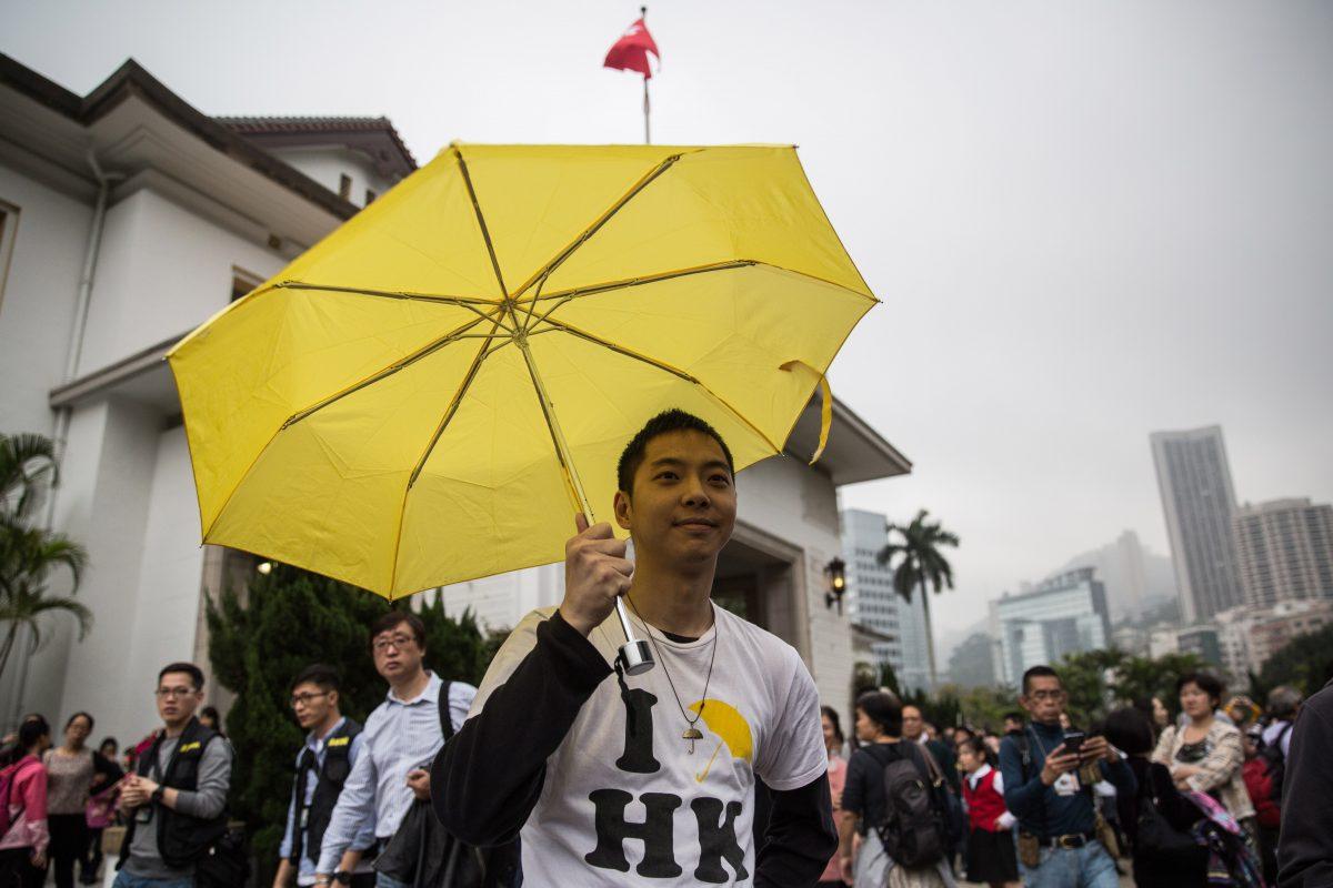 A pro-democracy protester raises his yellow umbrella, a symbol for the Umbrella Movement, at the annual open day for the Government House in Hong Kong on March 15, 2015. (Anthony Wallace/AFP/Getty Images)
