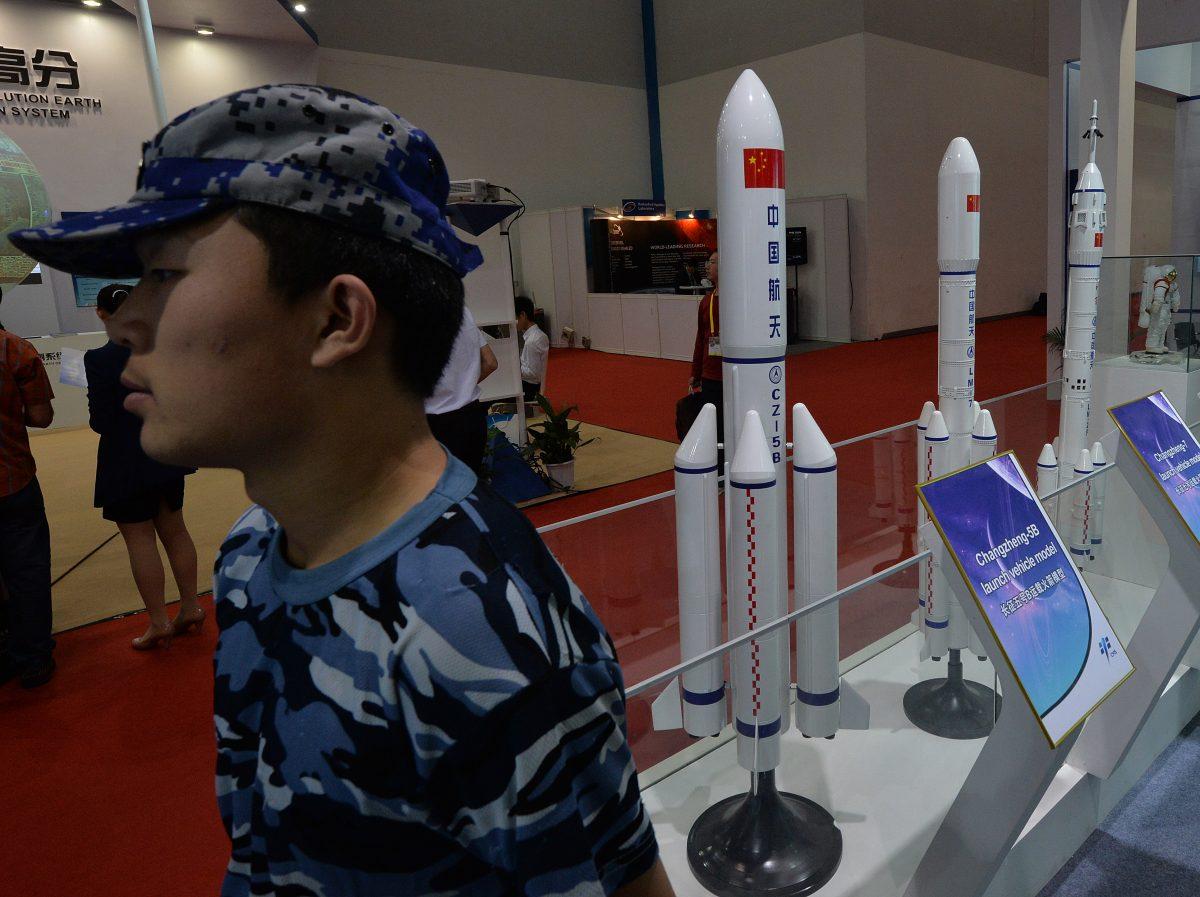 A security guard stands next to models of Chinese rockets on display Beijing on Sept. 24, 2013. The Chinese regime is testing weapons that could soon endanger satellites in all orbits. (Mark Ralston/AFP/Getty Images)