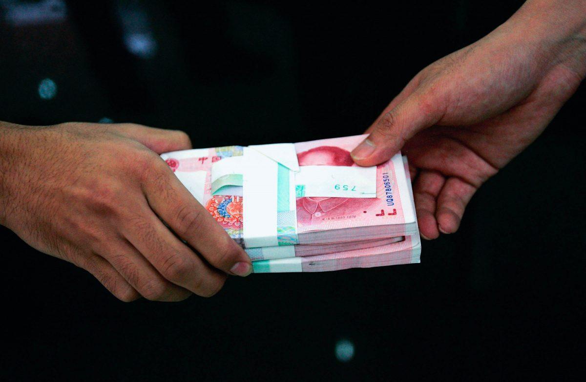  A clerk passes on stacks of Chinese yuan to another clerk at a bank in Beijing on July 22, 2005. (China Photos/Getty Images)