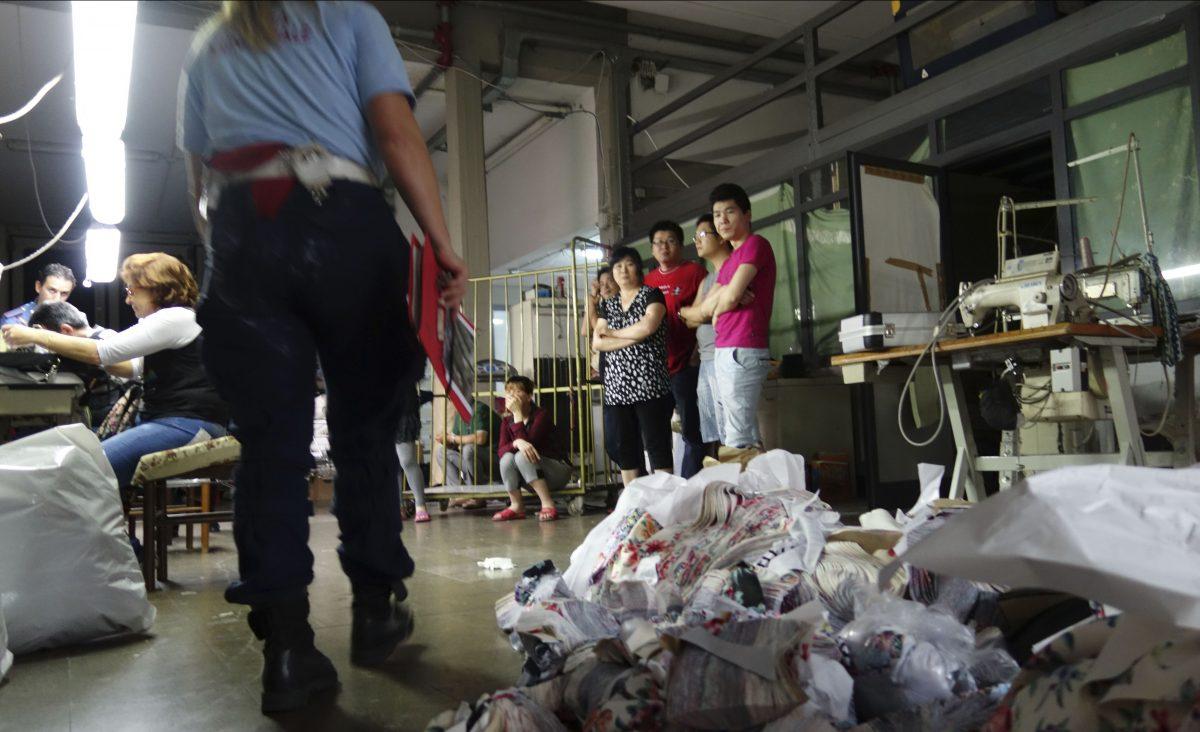 Municipal police captain Flora Leoni (L) approaches Chinese laborers at a garment factory during a raid in Prato, Italy, a town outside Florence with one of the highest concentrations of Chinese immigrants in Europe, on June 18, 2014. Italian police documented dozens of small Chinese-run businesses—many of them garment factories powered by under-paid immigrants working illegally—making remittances of hundreds of thousands of euros, despite declared earnings in the tens of thousands, or less. (Erika Kinetz/AP Photo)
