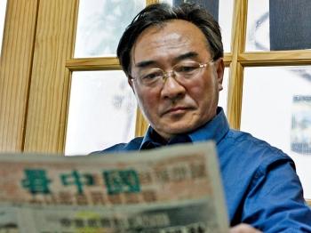 Sitting in a small office in Flushing, Zhang Kaichen reads one of the newspapers produced by the Chinese dissident community. (Matthew Robertson/The Epoch Times)
