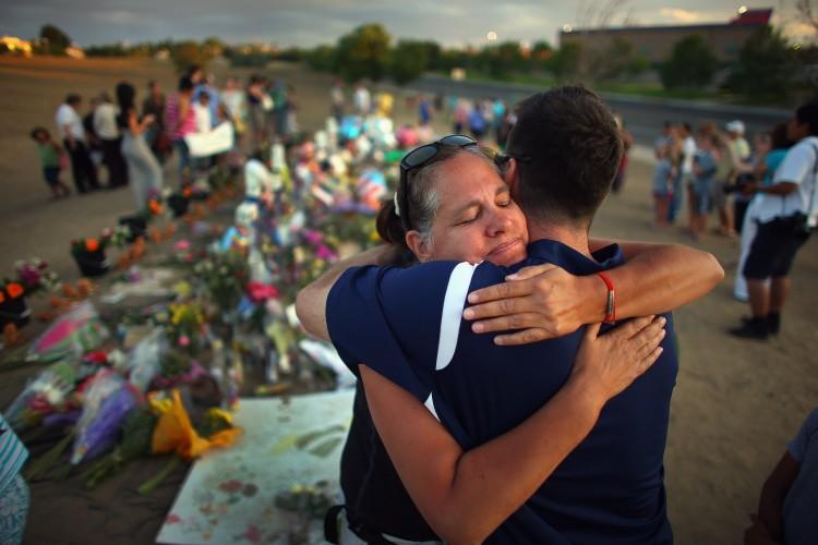 Julia Kouris hugs Steve Sundberg as they visit the memorial setup across the street from the Century 16 movie theater in Aurora, Colo., where a mass shooting took place on July 20, 2012. (Joe Raedle/Getty Images)
