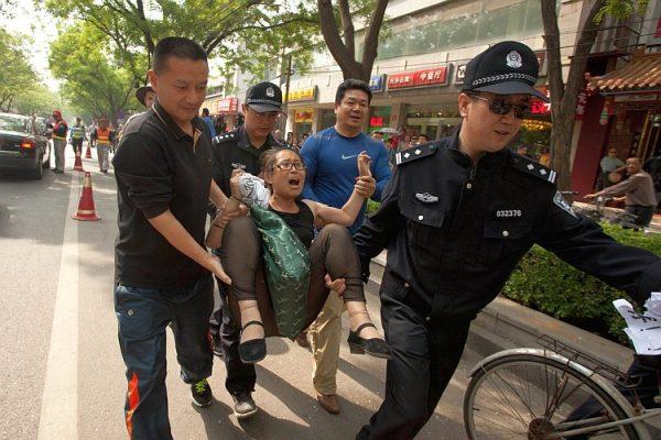 A petitioner is approached by police outside the hospital where Chinese activist Chen Guangcheng is staying in Beijing on May 5. The woman, who expressed displeasure with the Chinese regime's treatment of petitioners, asked to visit Chen. (Ed Jones/AFP/GettyImages)