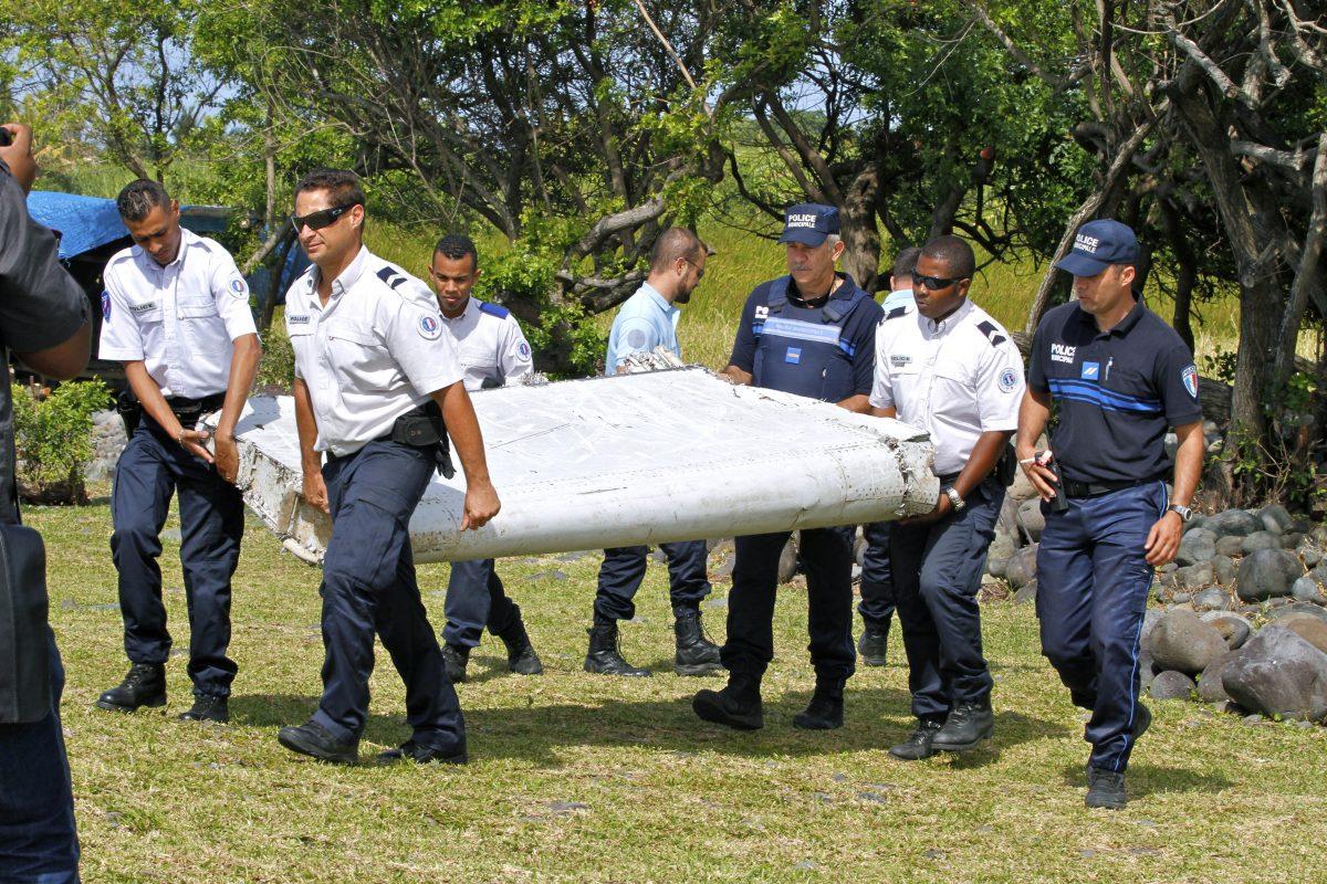 In this photo dated Wednesday, July 29, 2015, French police officers carry a piece of debris from a plane in Saint-Andre, Reunion Island. (AP Photo/Lucas Marie, File)