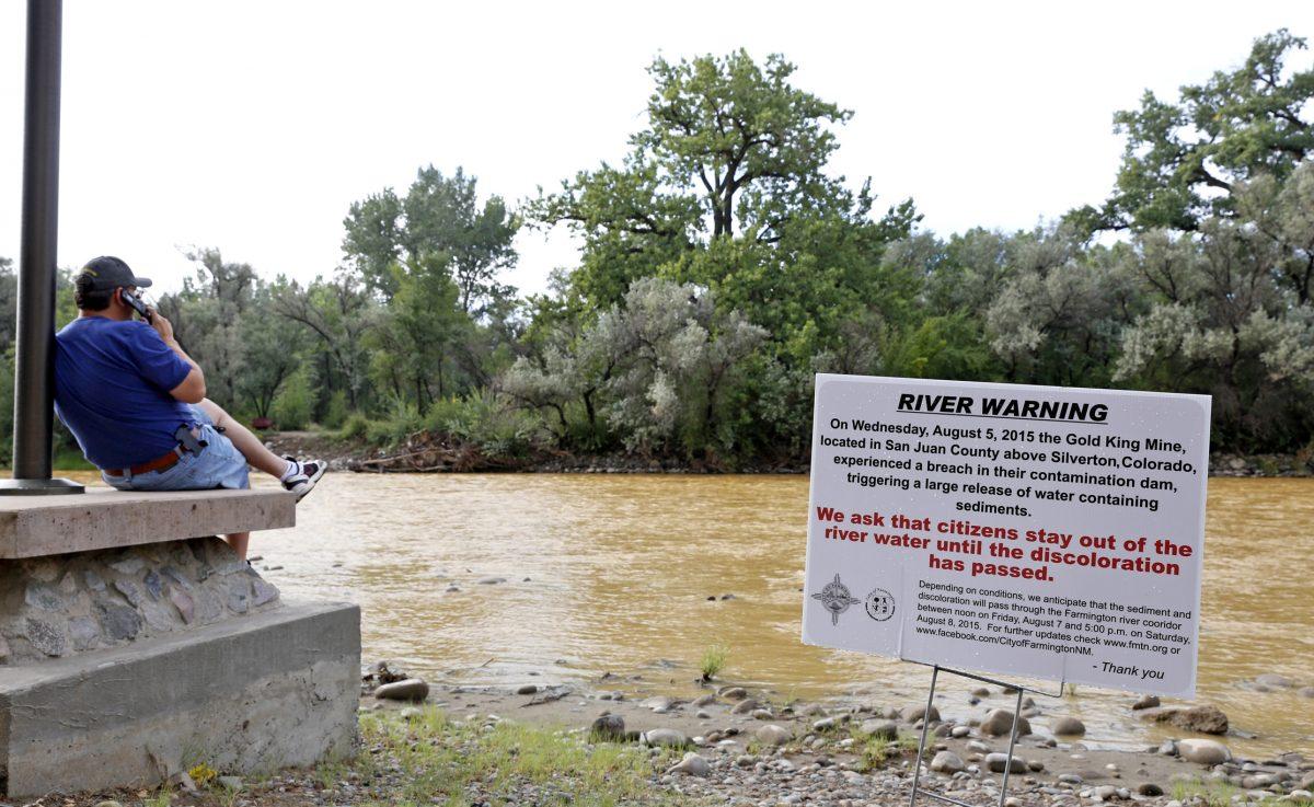A warning sign from the city is displayed in front of the Animas River as orange sludge from a mine spill upstream flows past Berg Park in Farmington, N.M., on Aug. 8, 2015. (Alexa Rogals/The Daily Times via AP)