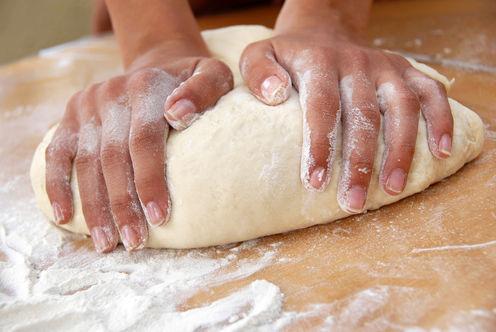 Using a sourdough starter to naturally leaven the bread, will further reduce the gluten content and activate food enzymes that make it much more digestible. (<a href="http://www.shutterstock.com/pic-51430996/stock-photo-female-hands-in-flour-closeup-kneading-dough-on-table.html?irgwc=1&tpl=77643-108110" target="_blank" rel="noopener">Shutterstock</a>)