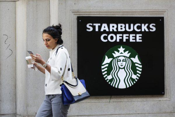 A woman walks out of a Starbucks Coffee with a beverage in hand in New York, on July 16, 2015.. (Mark Lennihan/AP Photo)
