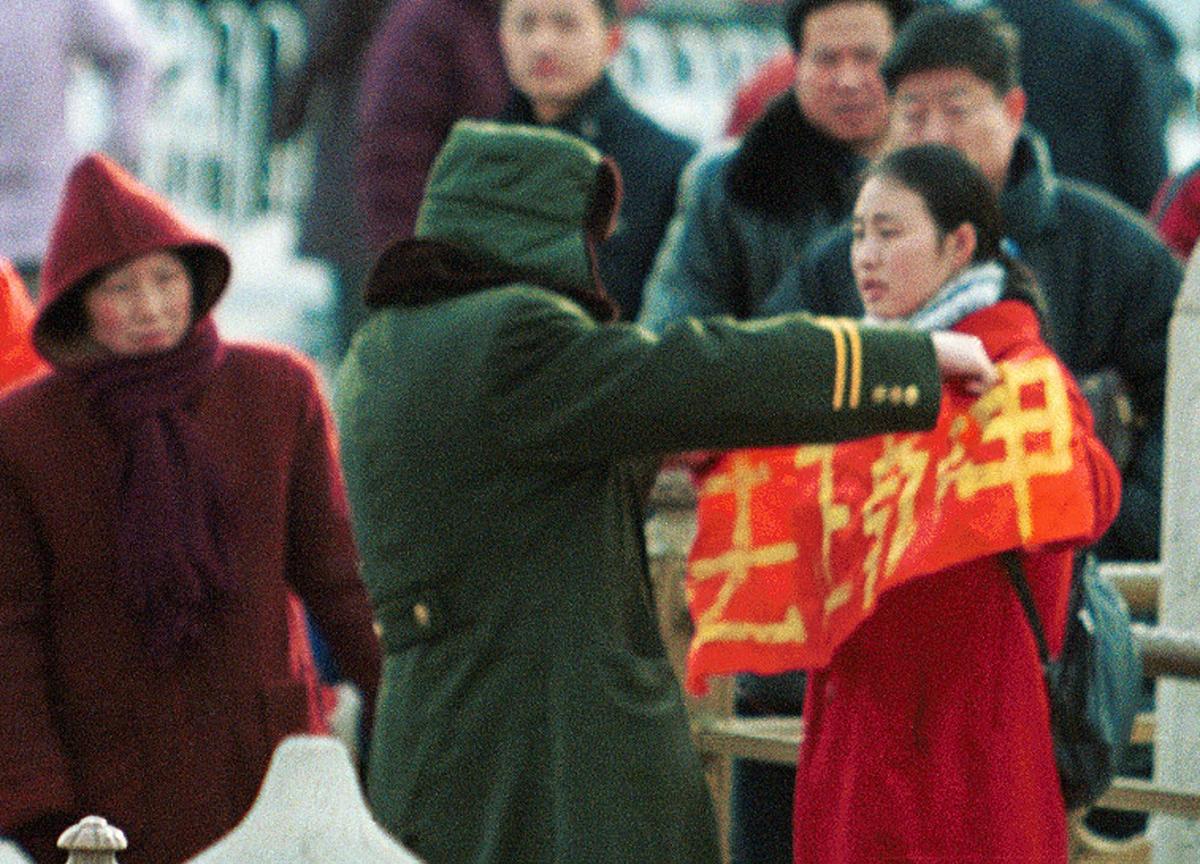 A woman who holds up a Falun Gong protest banner is detained by police at Beijing's Tiananmen Gate, on Jan. 25, 2001. (AP Photo/Greg Baker)