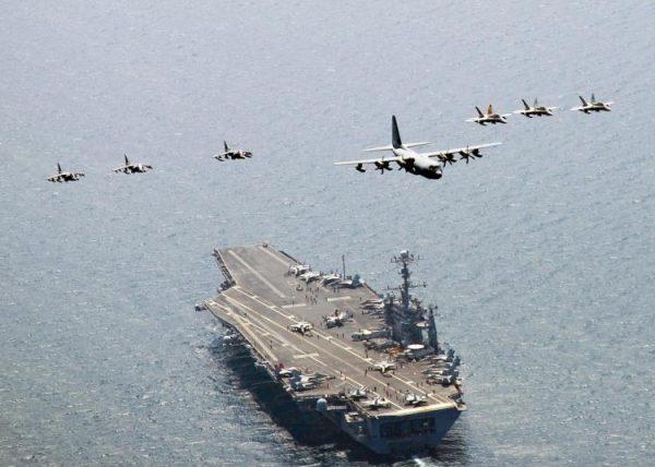 A US Marine Corps C-130 Hercules aircraft leads a formation of F/A-18C Hornet strike fighters and A/V-8B Harrier jets over the aircraft carrier USS George Washington off the coast of South Korea on July 27, 2010. (Mass Communication Specialist 3rd Class Charles Oki/U.S. Navy via Getty Images)