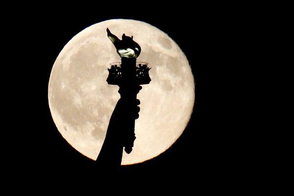 A blue moon rises behind the torch of the Statue of Liberty seen from Liberty State Park in Jersey City, N.J., on July 31, 2015. (Julio Cortez/AP Photo)