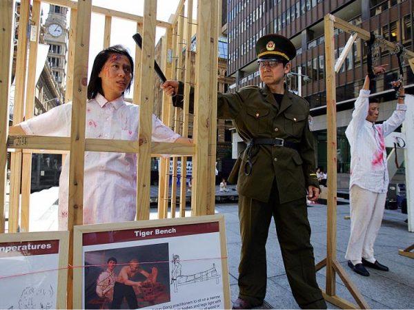 Falun Gong members re-enact Chinese torture methods used on their practitioners during a demonstration in Sydney. According to the Chinese regime, such torture is completely legal. (Torsten Blackwood/AFP/Getty Images)