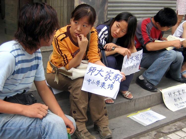College students and graduates sit by a sidewalk offering their tutoring services, in Xi'an, central China's Shaanxi Province, in this undated photo. Millions of college graduates in China are finding themselves with no jobs waiting, or end up performing work for which they are overqualified. (STR/AFP/Getty Images)