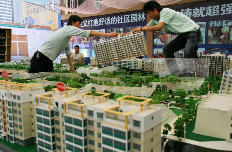 Two workers move a building model during a real estate fair in Xian of Shaanxi Province, China, in 2007. (China Photos/Getty Images)