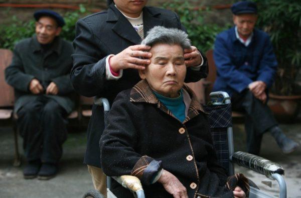 An attendant gives a massage to a senior citizen in an elder care center on Oct. 16, 2007, in Chongqing, China. (China Photos/Getty Images)