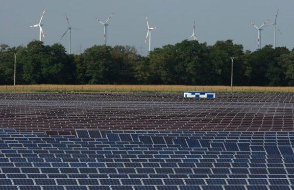 Wind turbines spin behind a field of solar cell panels.  (Sean Gallup/Getty Images)