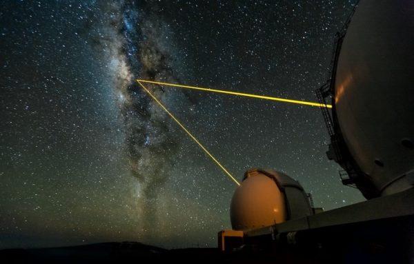 The two W. M. Keck Telescopes in Hawaii observe the galactic centre. Using the adaptive optics technique, the lasers create an artificial star in the Earth’s upper atmosphere, which allows measurement of the lower atmosphere's blurring effects (that makes stars twinkle in the night sky). The blurring gets corrected in real-time with the help of a deformable mirror. (Ethan Tweedie)