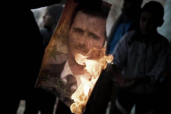 A member of the Free Syrian Army holds a burning portrait of President Bashar al-Assad in Al-Qsair, on Jan. 25, 2012. In a recent interview, Syrian Assad scorned foreign intervention in the nation's civil war. (Alessio Romenzi/AFP/Getty Images)