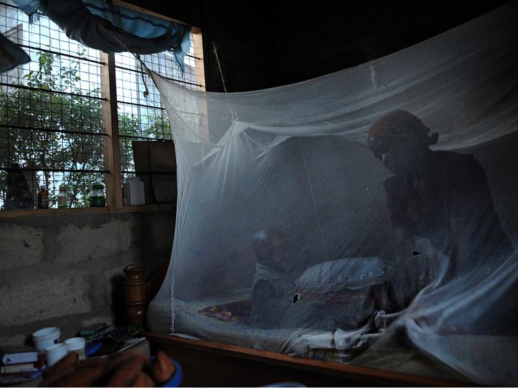 A mother and her child sit on a bed covered with a mosquito net near Bagamoyo, 50 miles north of Tanzanian capital Dar es Salaam. Mosquito-borne malaria kills about one child every thirty seconds in Africa; nets are one of the cheapest and simplest solutions. (Tony Karumba/AFP/Getty Images)