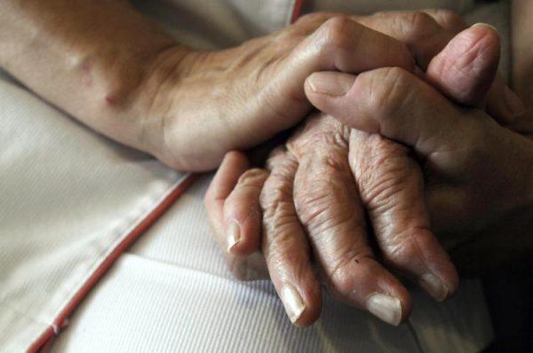 Woodruff said that despite the alarming nature of uncovering similarities between the brain's response to COVID-19 and its response to dementia diseases, this discovery also meant that a possible treatment already exists. A nurse holds the hands of a patient in a 2009 file photo. (Sebastien Bozon/AFP/Getty Images)