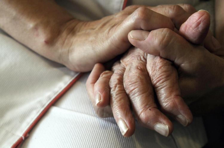 A nurse holds the hands of a patient in a 2009 file photo. (Sebastien Bozon/AFP/Getty Images)