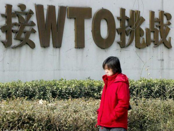 A Chinese woman walks past a billboard boasting of China's World Trade Organization membership. (Goh Chai Hin/AFP/Getty Images)