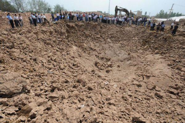 People gather around a crater of what used to be the Jingxin Mining company, which produced and processed quartz sand in Fengyang, Anhui Province, China in this undated photo. China is the world's largest producer of rare earth minerals. (AFP/AFP/Getty Images)