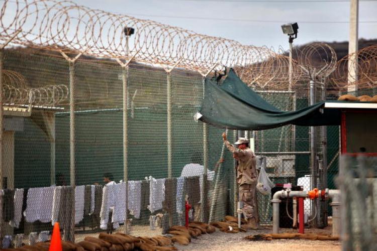 A guard leans on a fence talking to a Guantanamo detainee, inside the open yard at Camp 4 detention center, at the U.S. Naval Base, in Guantanamo Bay, Cuba, Wednesday, Jan. 21, 2009. (Brennan Linsley-Pool/Getty Images)