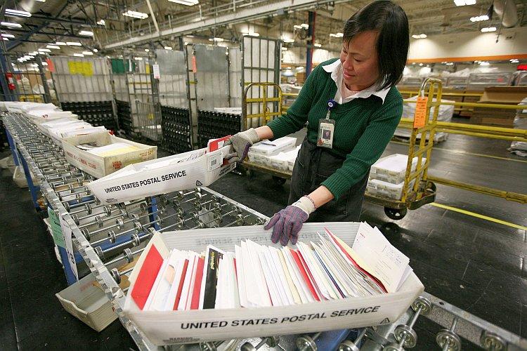 U.S. postal worker Tin Aung moves boxes of letters and cards at the U.S. Post Office sort center in San Francisco, in 2008. (Justin Sullivan/Getty Images)