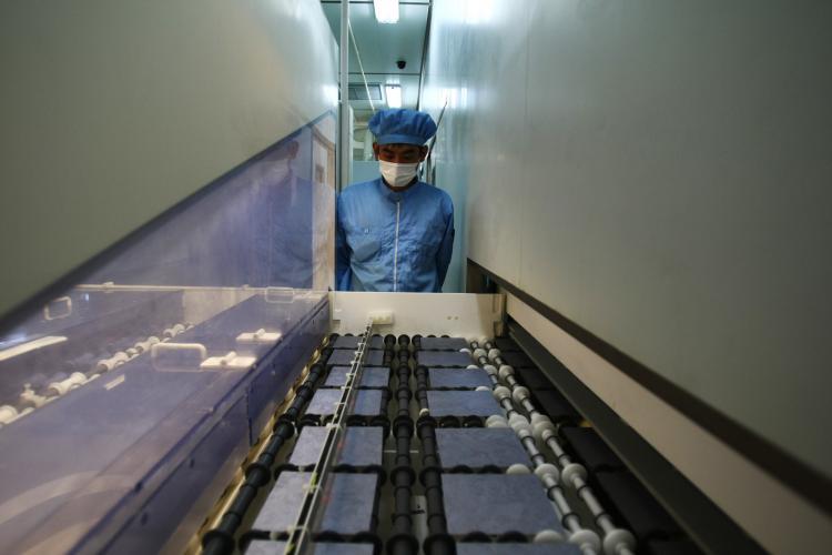 A worker controls the production line for silicon chips using for making photoelectric board products, in Baoding, China, on June 24, 2009. (Feng Li/Getty Images)