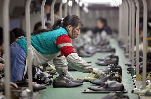 A worker pulls a pair of shoes from a production line in a factory located in Chengdu, China. (China Photos/Getty Images)