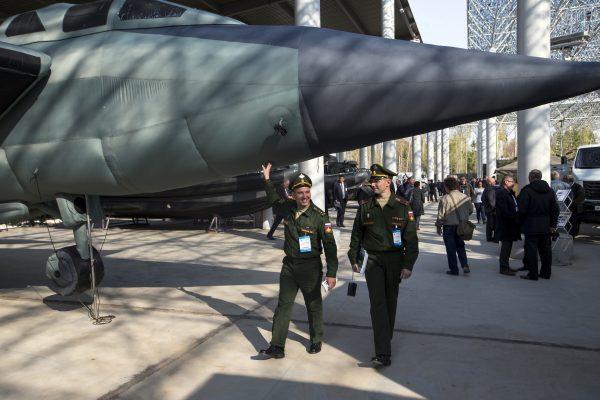 A Russian army officer smiles as he touches an inflatable mock jet fighter on display during an Innovation exhibition of the Russian Defense Ministry in Kubinka, outside Moscow, on Oct. 5, 2015. (Pavel Golovkin/AP Photo)