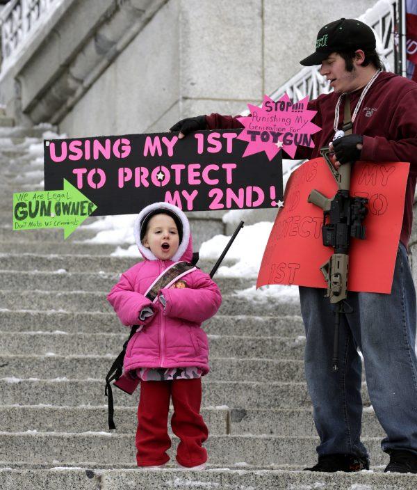 Gun-rights activist Jotham holds his M&P15 rifle and a sign with his daughter, Valina, 3, carrying her Savage .22 caliber during a "National Day of Resistance" rally at the Utah State Capitol in Salt Lake City, Utah, on Feb. 23, 2013. (Rick Bowmer/AP Photo)