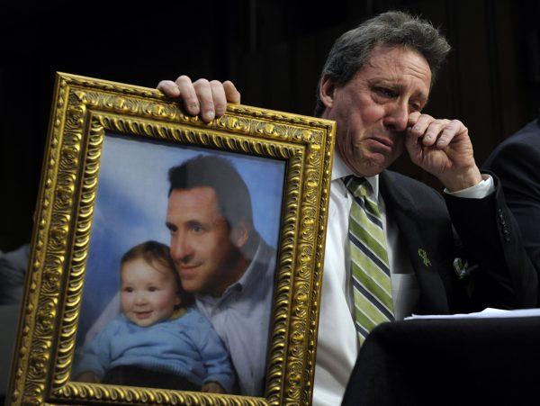 Neil Heslin, the father of Jesse, a 6-year-old boy, who was killed in the Sandy Hook massacre in Newtown, Conn., holds a picture of them together while testifying on Capitol Hill in Washington on Feb. 27, 2013. (Susan Walsh/AP Photo)