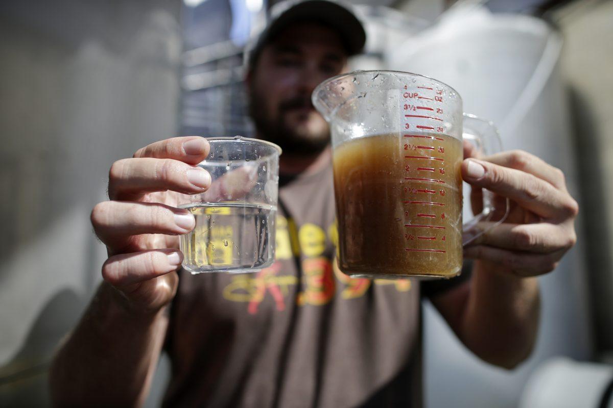 A man holds a container of non-potable water before it is treated, right, and after, left, in Escondido, Calif., on Sept. 30, 2015. (Gregory Bull/AP Photo)