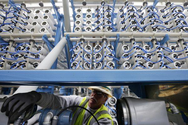 A worker adjusts equipment among some of the 2000 pressure vessels used to convert seawater into fresh water through reverse osmosis in the western hemisphere's largest desalination plant, in Carlsbad, Calif., on March 11, 2015. (Gregory Bull/AP Photo)