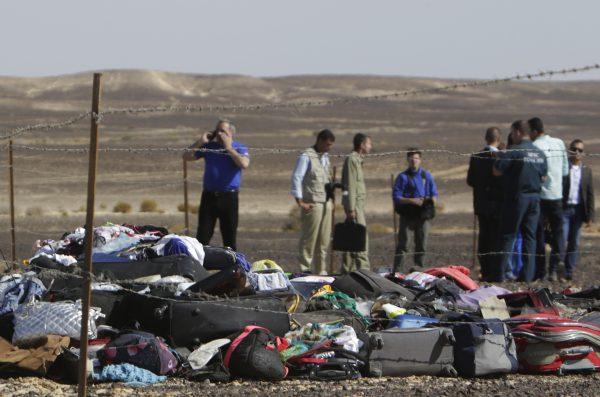 Russian investigators stand near debris, luggage and personal effects of passengers a day after a passenger jet bound for St. Petersburg in Russia crashed in Hassana, Egypt, on Sunday, Nov. 1, 2015. (AP Photo/Amr Nabil)