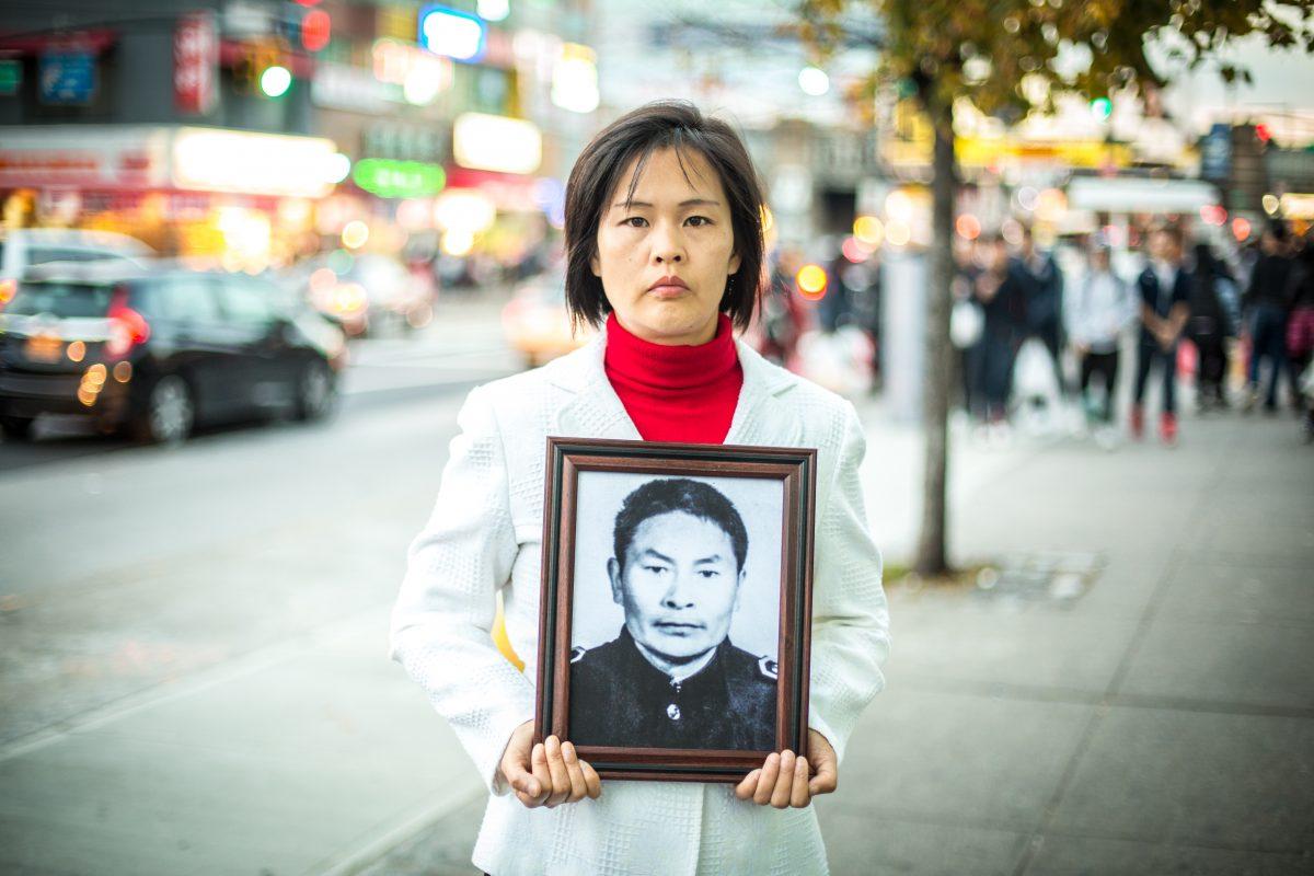 Jiang Li in the Flushing neighborhood of Queens, N.Y., on Nov. 1, 2015, holds a photo of her father, who was killed by the Chinese Communist Party in China for practicing Falun Gong. (Benjamin Chasteen/The Epoch Times)