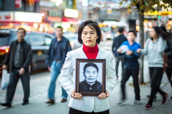 Jiang Li holds a photo of her father who was killed by the Chinese Communist Party in China for practicing Falun Gong, in the Flushing neighborhood of Queens, N.Y., on Nov. 1, 2015. (Benjamin Chasteen/Epoch Times)