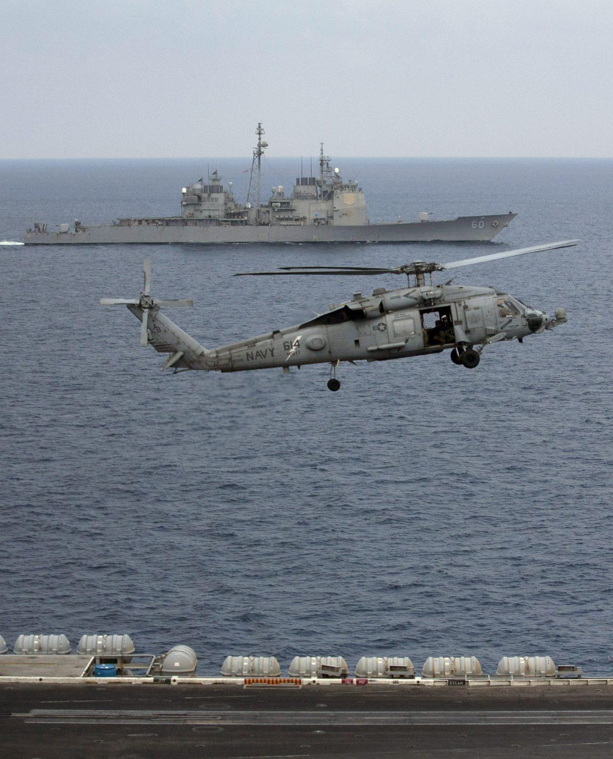 A U.S. Navy helicopter approaches to land on the deck of the aircraft carrier USS Theodore Roosevelt (CVN 71), as the USS Normandy sails in the Bay of Bengal during Exercise Malabar 2015, some 152 miles off the eastern coast of Chennai, India, on Oct. 17, 2015. Naval warships, aircraft carriers, and submarines from the United States, India, and Japan are conducting joint military exercises off India's east coast, signaling the growing strategic ties between the three navies as they face up to a rising China. (Arun Sankar K./AP Photo)
