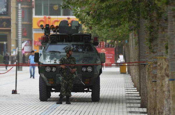 A member of the Chinese paramilitary police stands in front of an armoured vehicle in Hotan, Xinjiang region of China, in a file photo. The Chinese regime has deepened its suppression of the Uyghur ethnic group in the region. (Greg Baker/AFP/Getty Images)