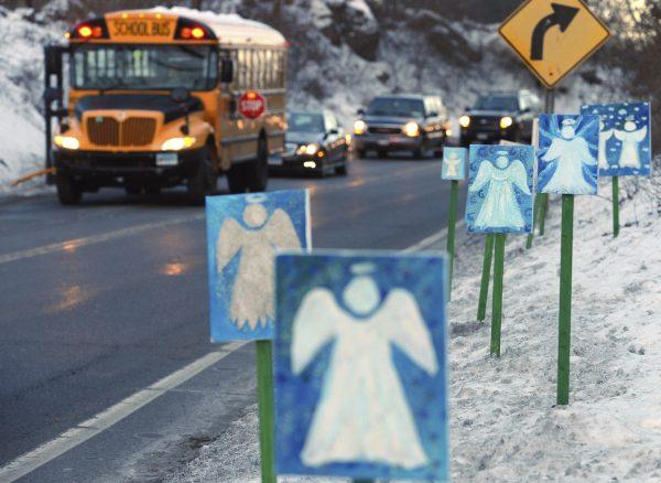 A bus traveling from Newtown in Connecticut stops near 26 angel signs posted along the roadside in Monroe, Jan. 3, 2013, on the first day of classes for Sandy Hook Elementary School students since the Dec. 14, 2012, shooting. (AP Photo/Jessica Hill, File)